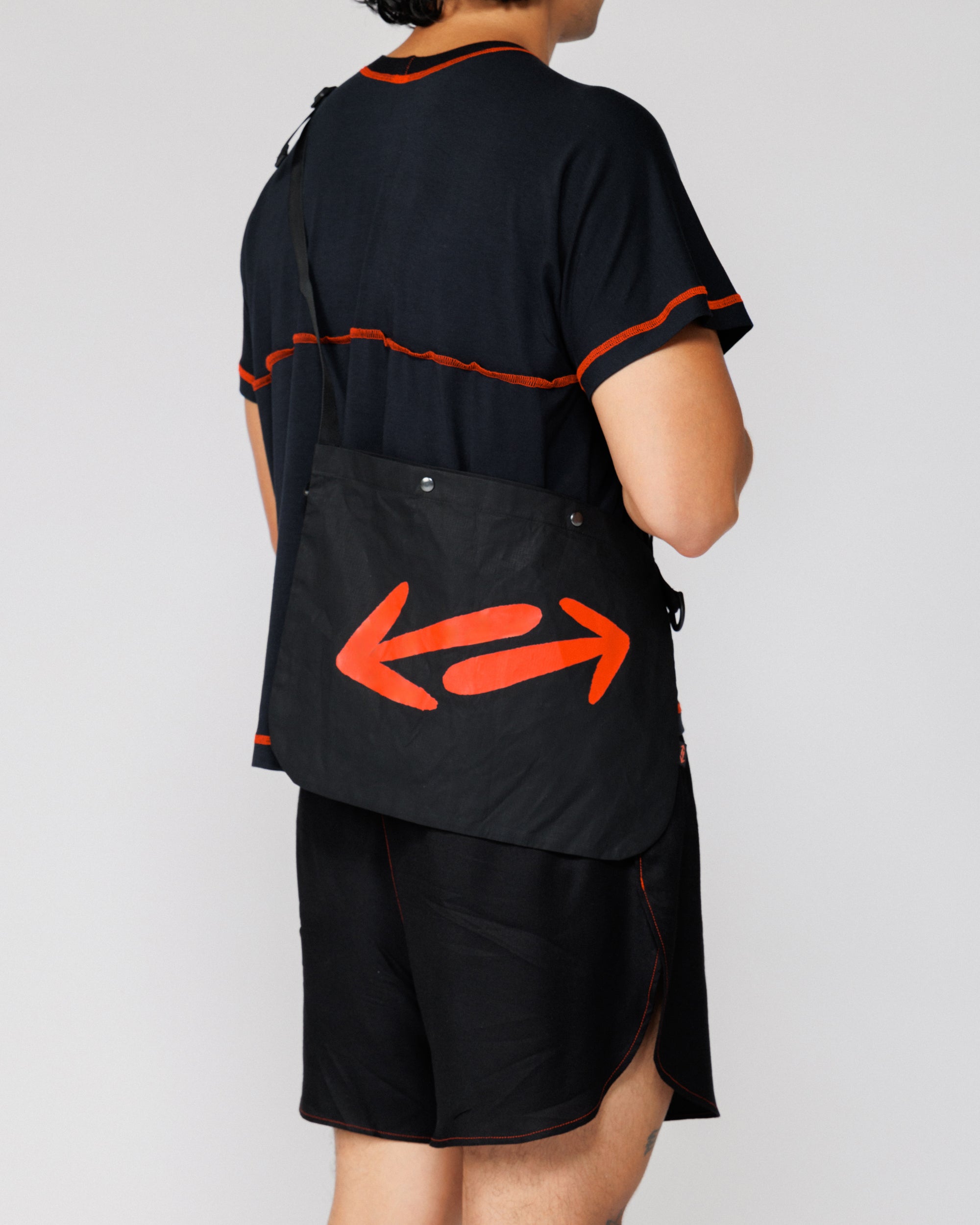 Outnback Musette in black worn on the back, cropped view of the red double-arrow print