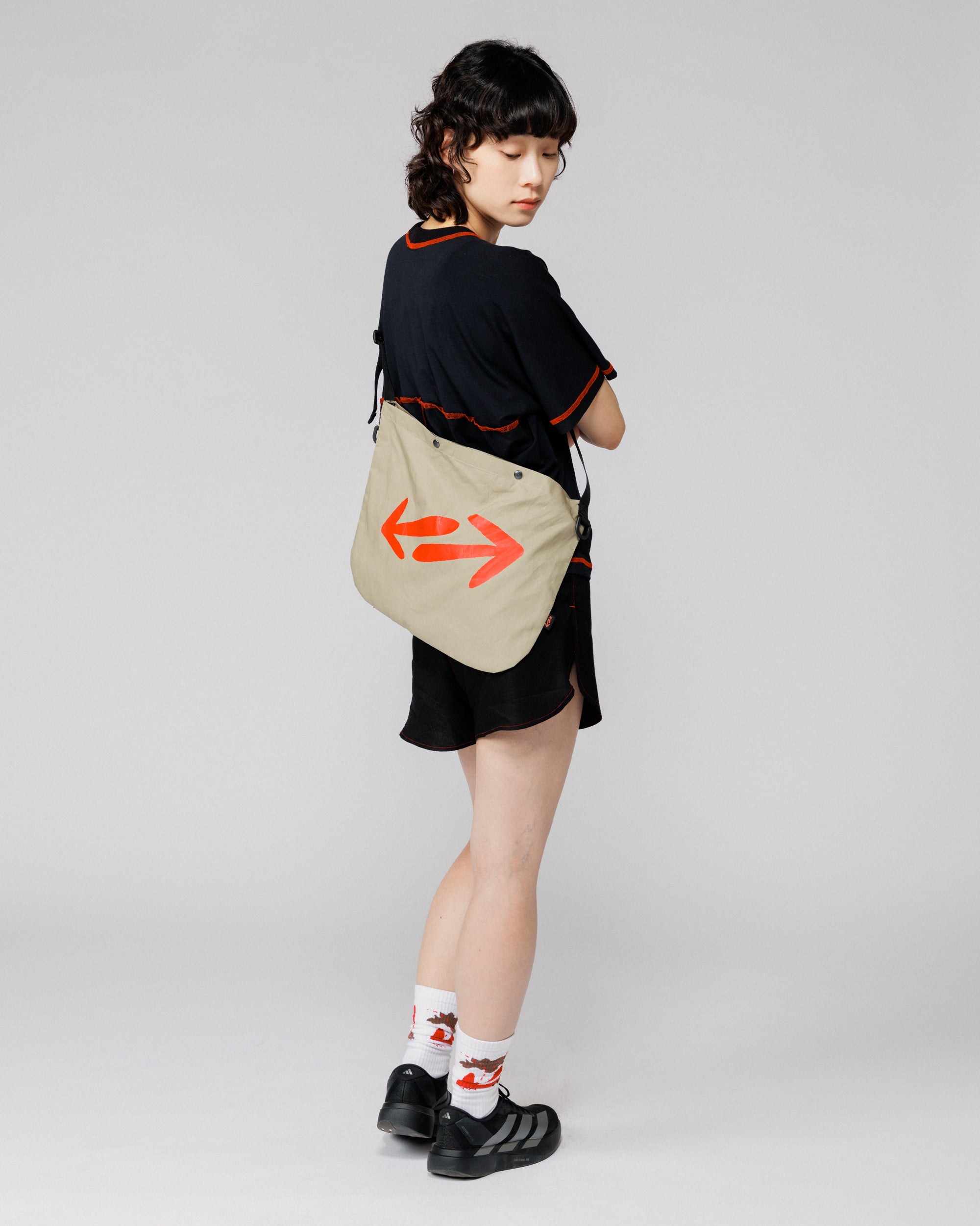 Outnback Musette in stone worn across the back, full-body rear view on model showing double arrow logo