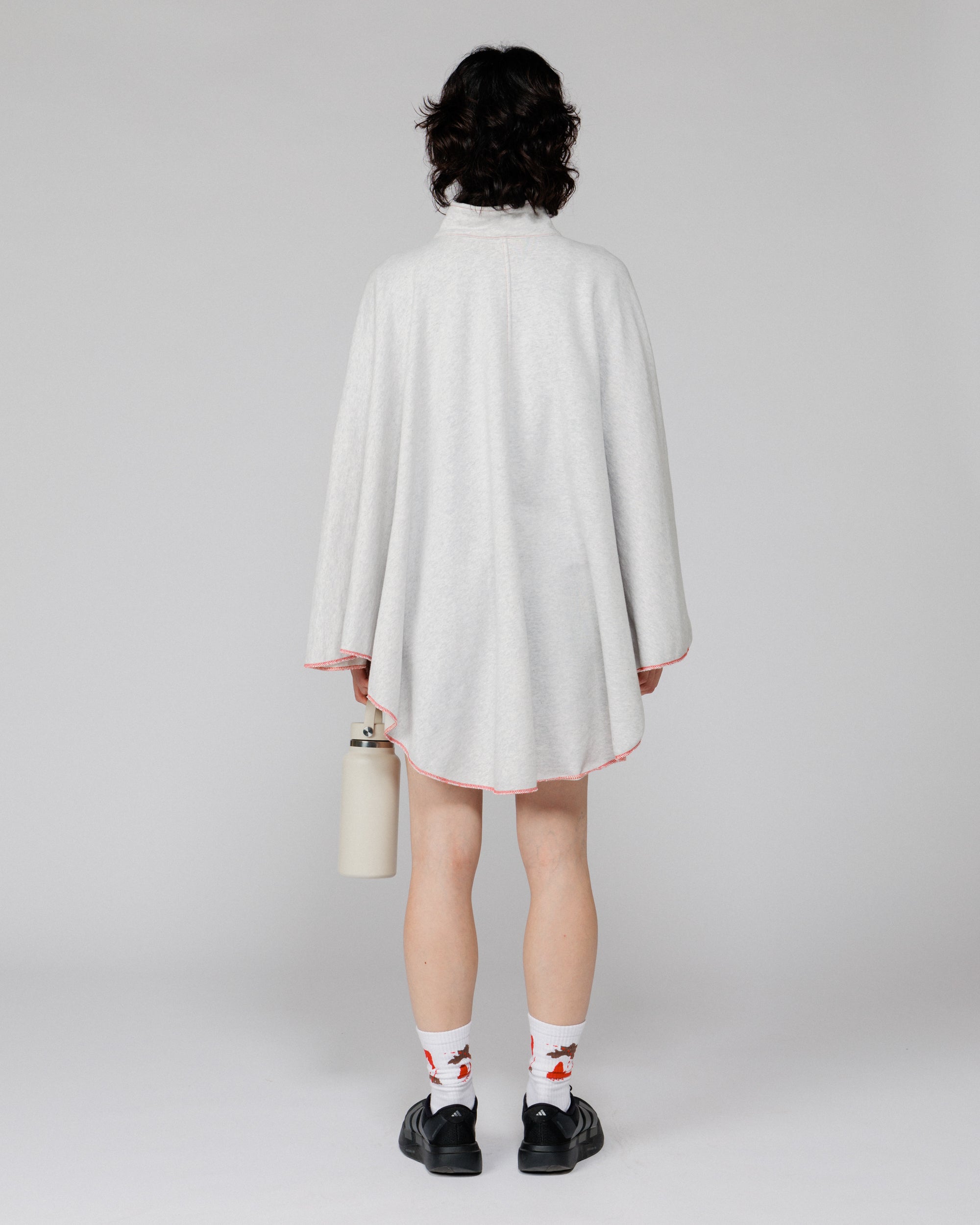 Model wearing the Outnback Recovery Cape in marl grey, back view showing the curved hem