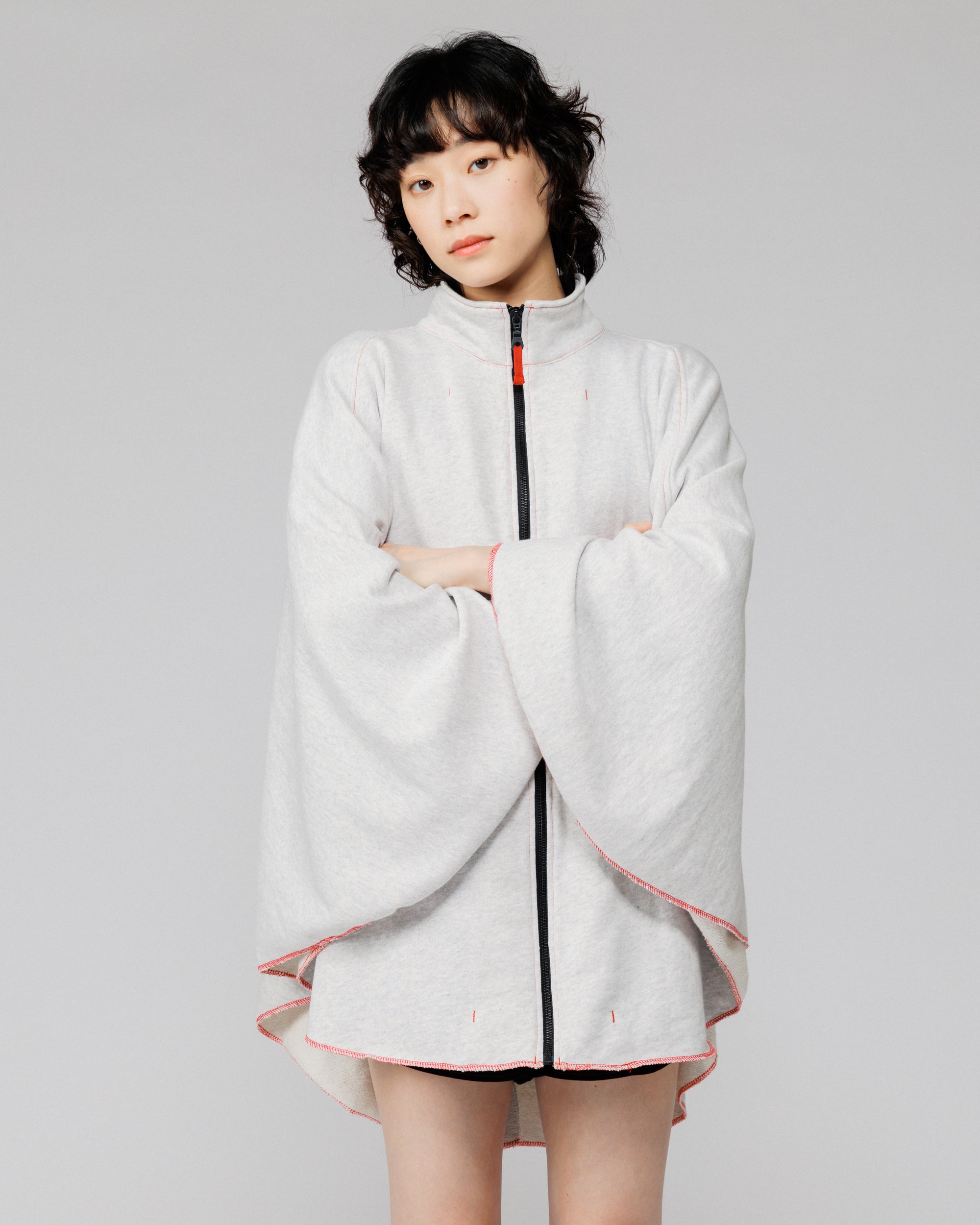 Cropped view of the Outnback Recovery Cape in marl grey with arms wrapped inside the cape