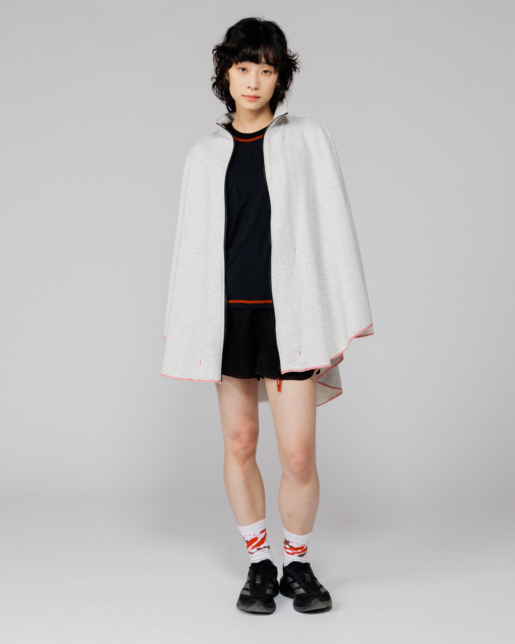 Model wearing the Outnback Recovery Cape in marl grey unzipped and open over a black tee