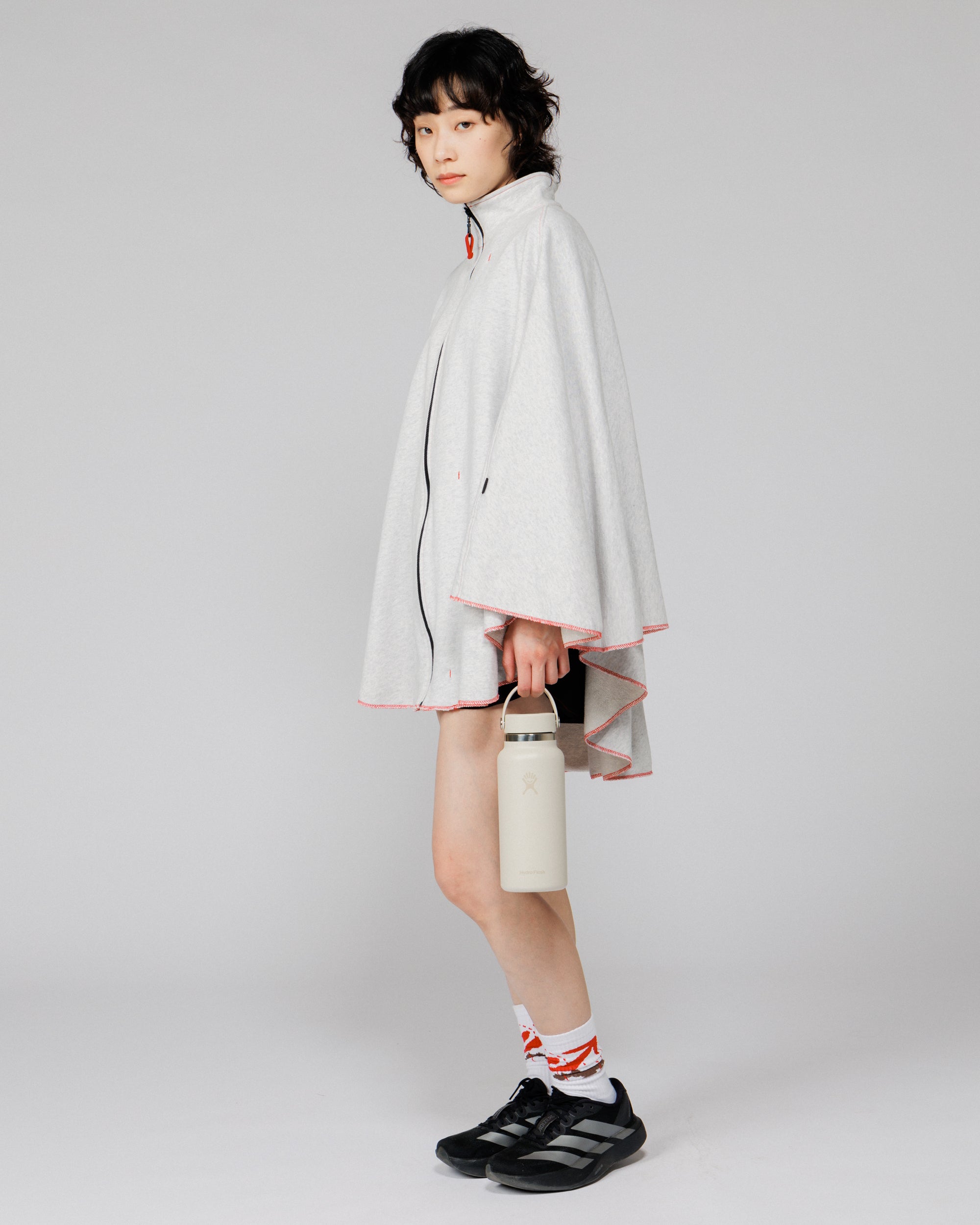 Model wearing the Outnback Recovery Cape in marl grey, three-quarter turn showing the side and back drape