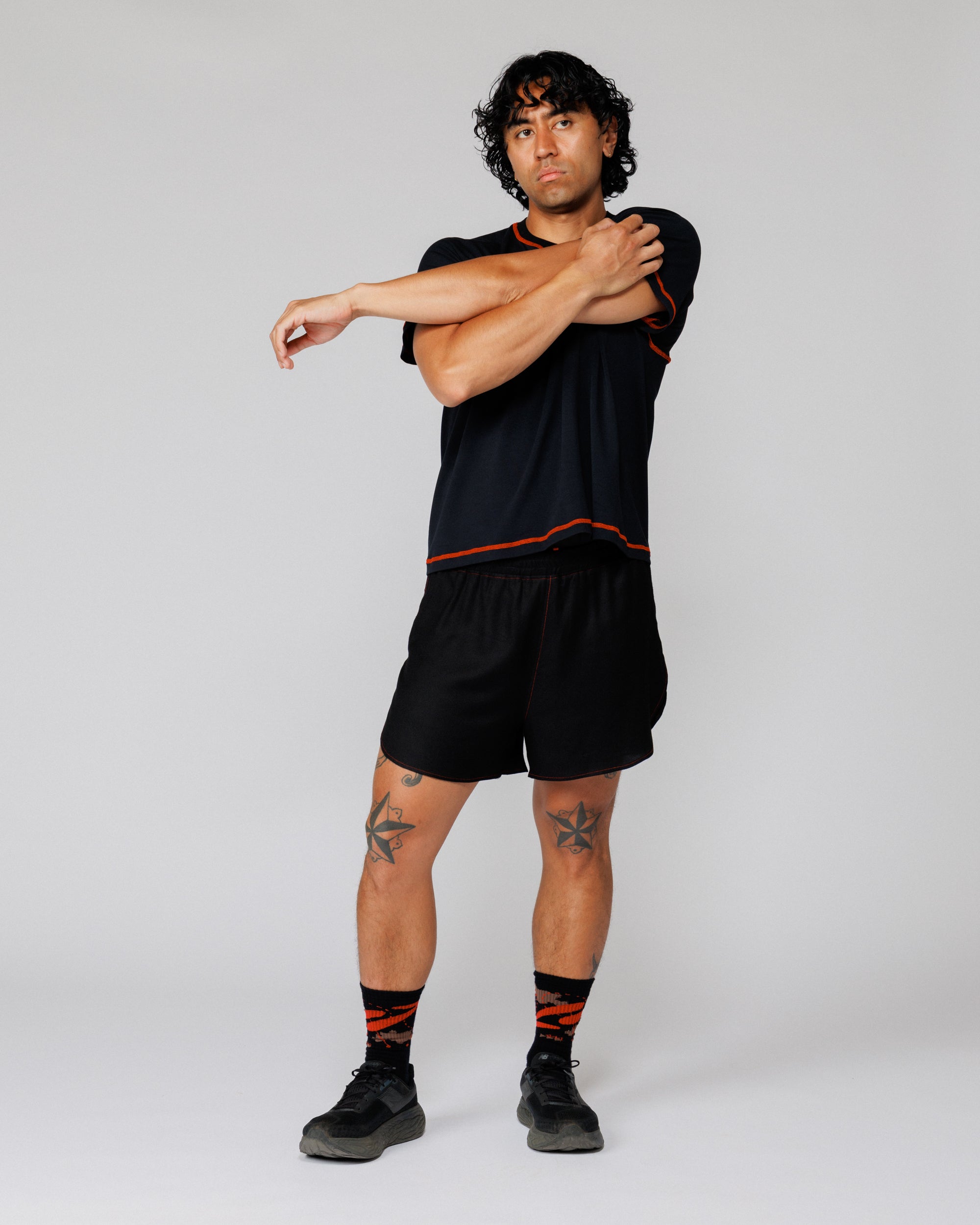 Outnback Running Short in black, on model stretching before a run