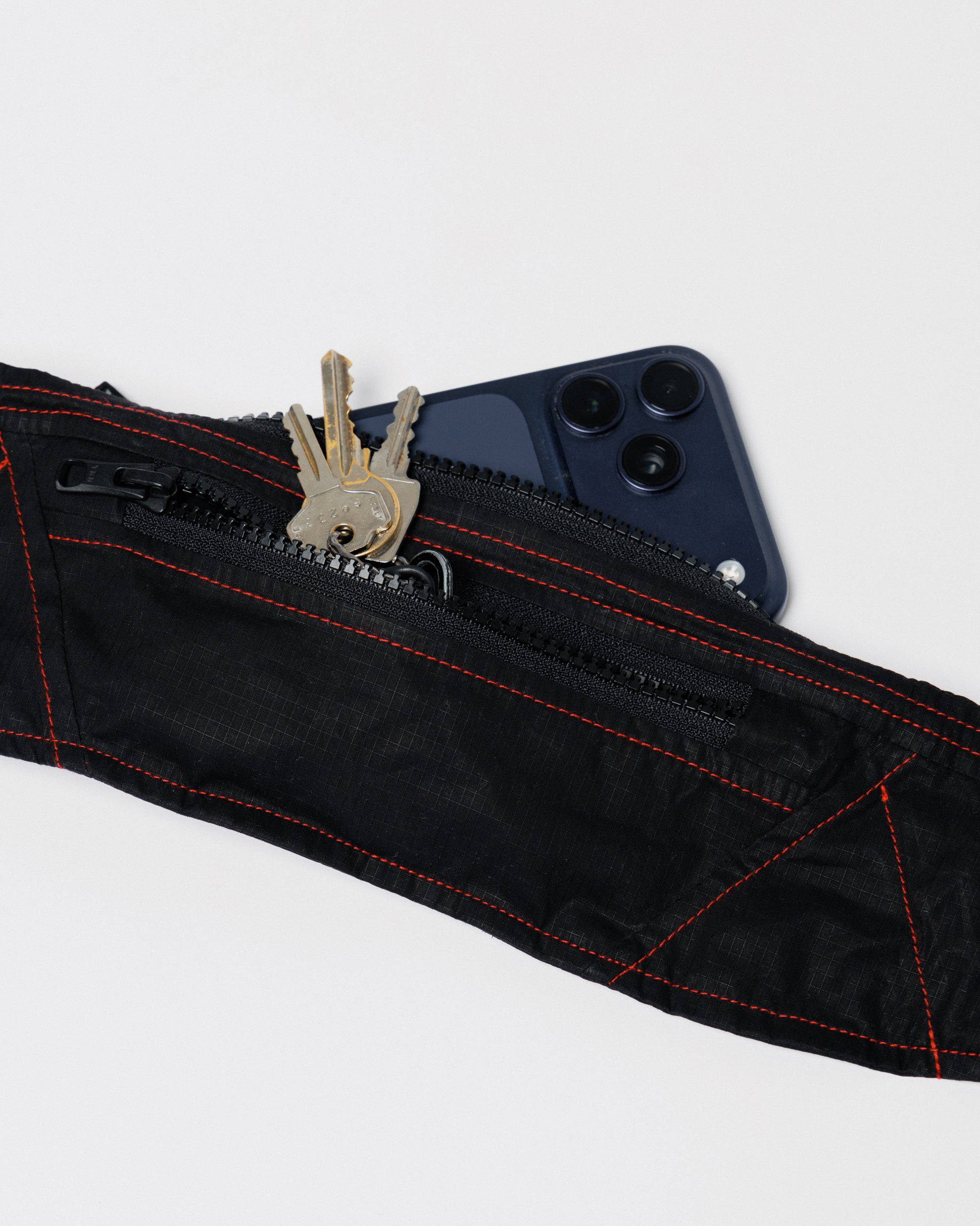 Outnback Running Strap in black, pocket holding keys and a phone