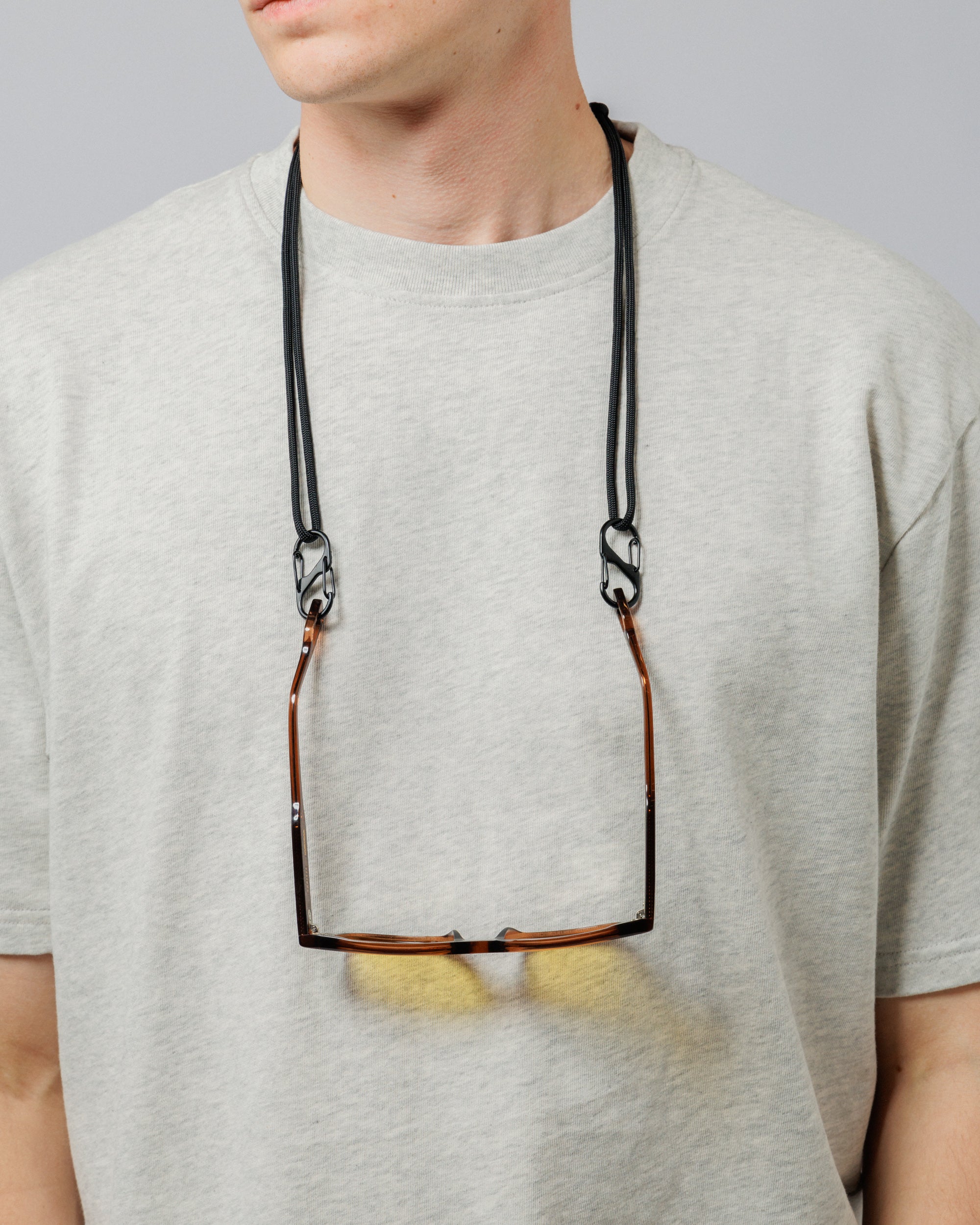 Solaris Sunglasses in coconut hanging from paracord sunglasses strap worn around neck