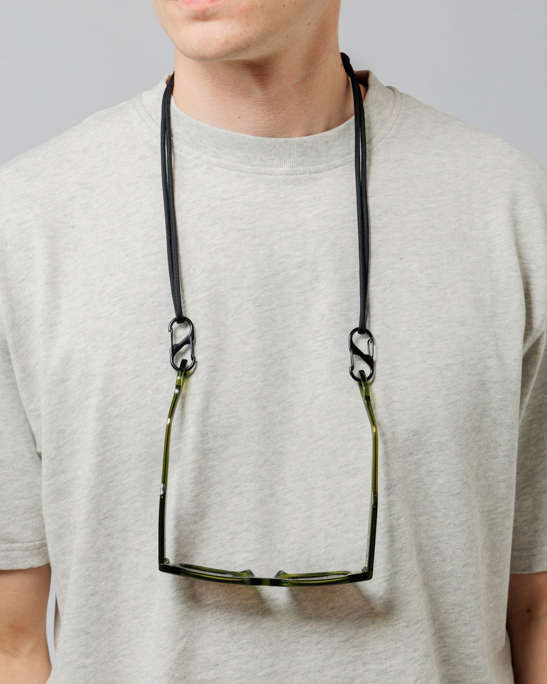 Solaris Sunglasses in khaki hanging from paracord sunglasses strap worn around neck