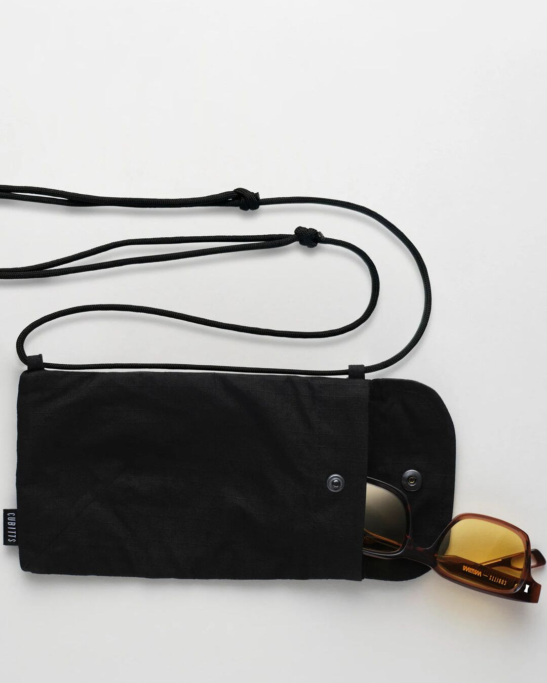 Cubitts x WAWWA Sunnies Sling in black, open with Solaris Sunglasses inside