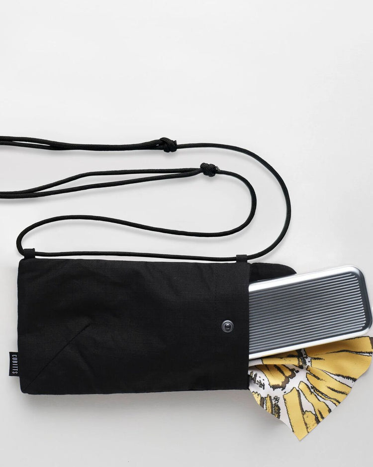 Black Sunnies Sling holding a tin and lens cloth, showing capacity